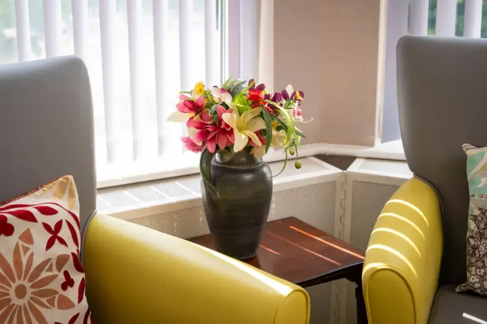 Oaklands Residential Care Home, Methley, Leeds | A vase of flowers is sitting on a table next to two chairs.