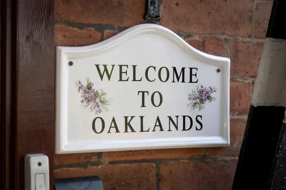 Oaklands Residential Care Home, Methley, Leeds | A welcome to oaklands sign hangs on a brick wall