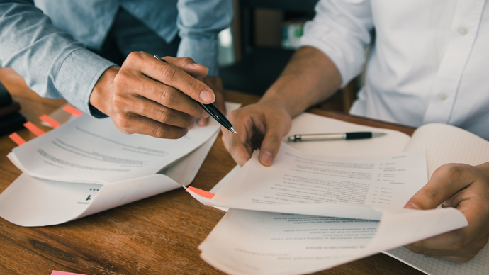 Two people are sitting at a table looking at papers.
