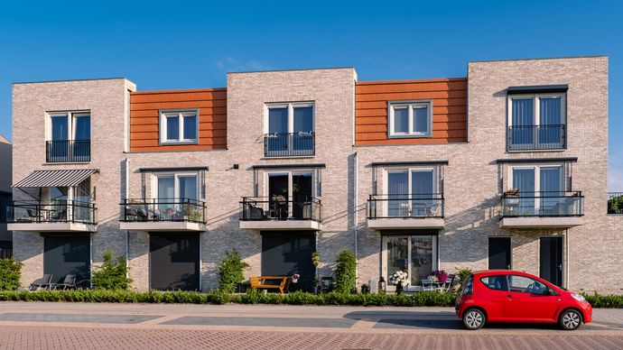 A red car is parked in front of a row of houses.