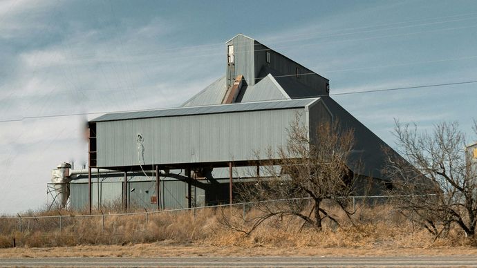 A large building is sitting in the middle of a field