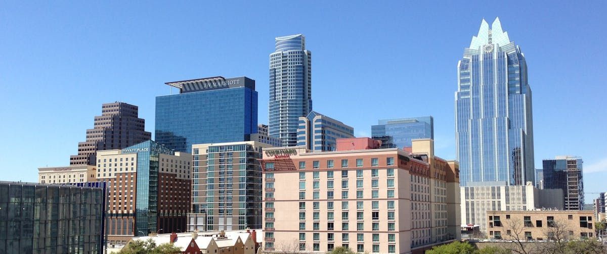A city skyline with a lot of tall buildings and a blue sky