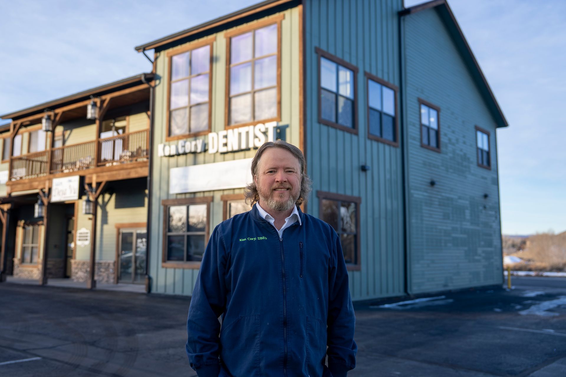 Man in white shirt and striped tie smiles at the camera. Neutral background.