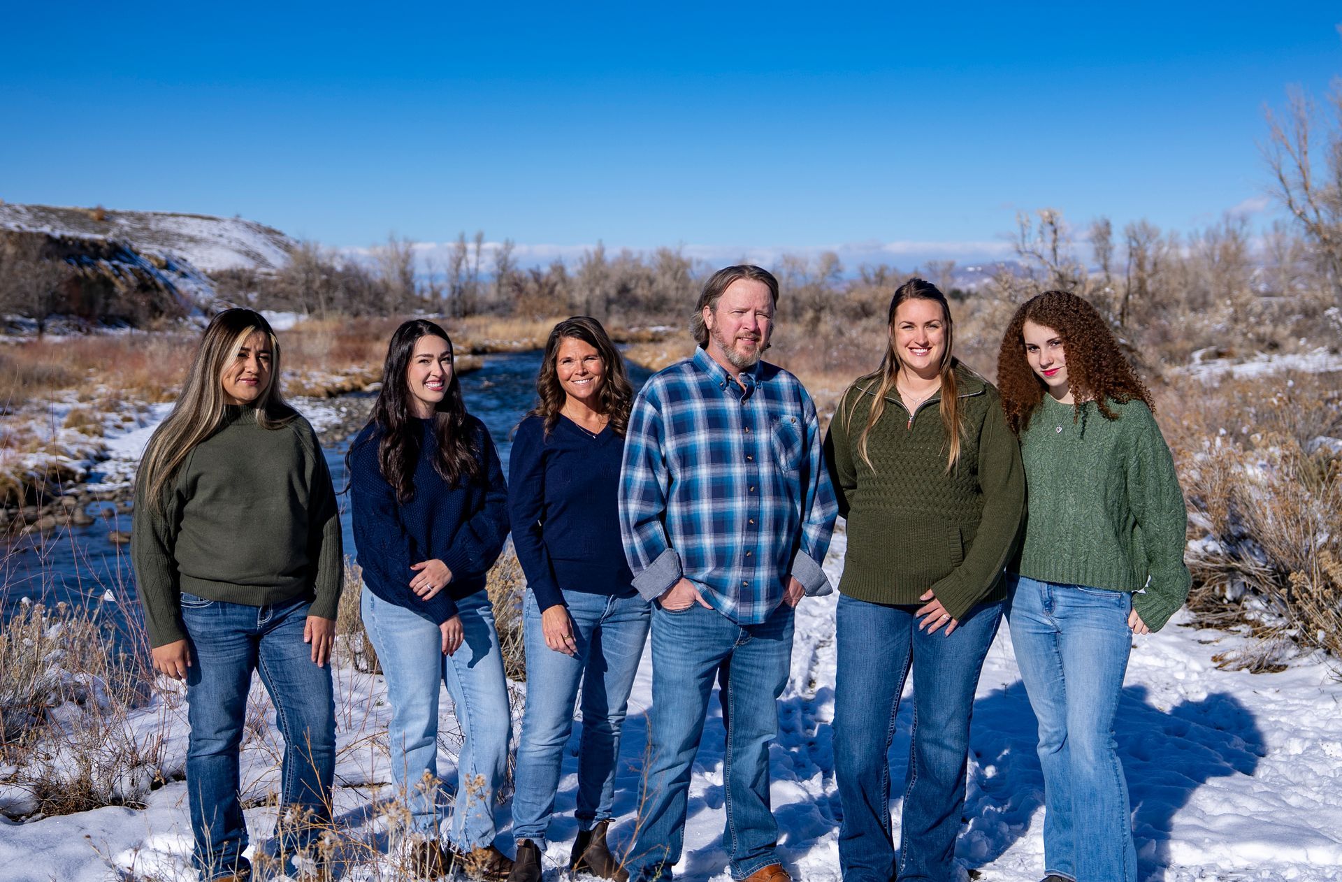 Woman smiling, making heart shape with hands, wearing glasses.