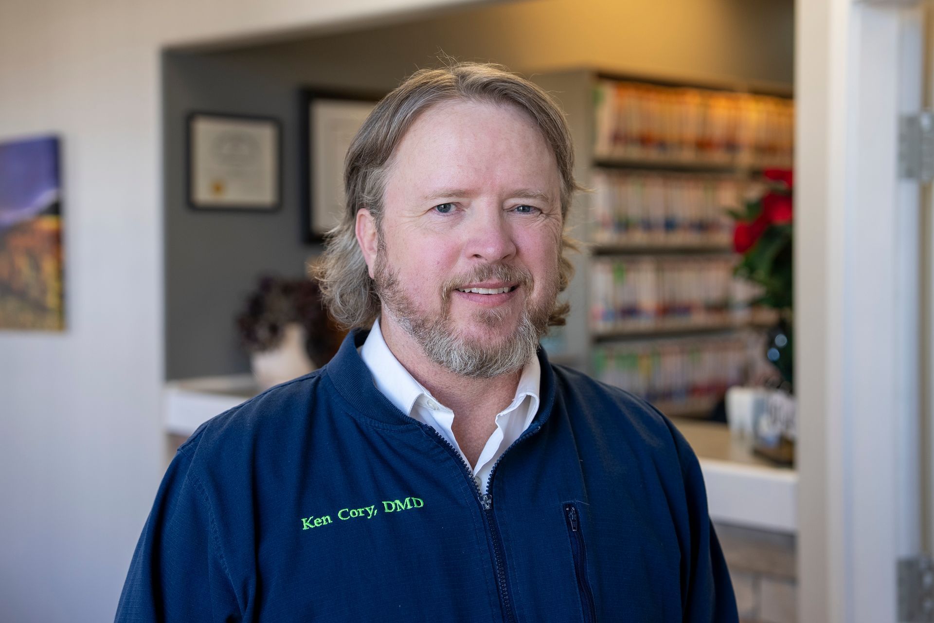 Man in a white shirt and blue striped tie smiles, looking towards the viewer.