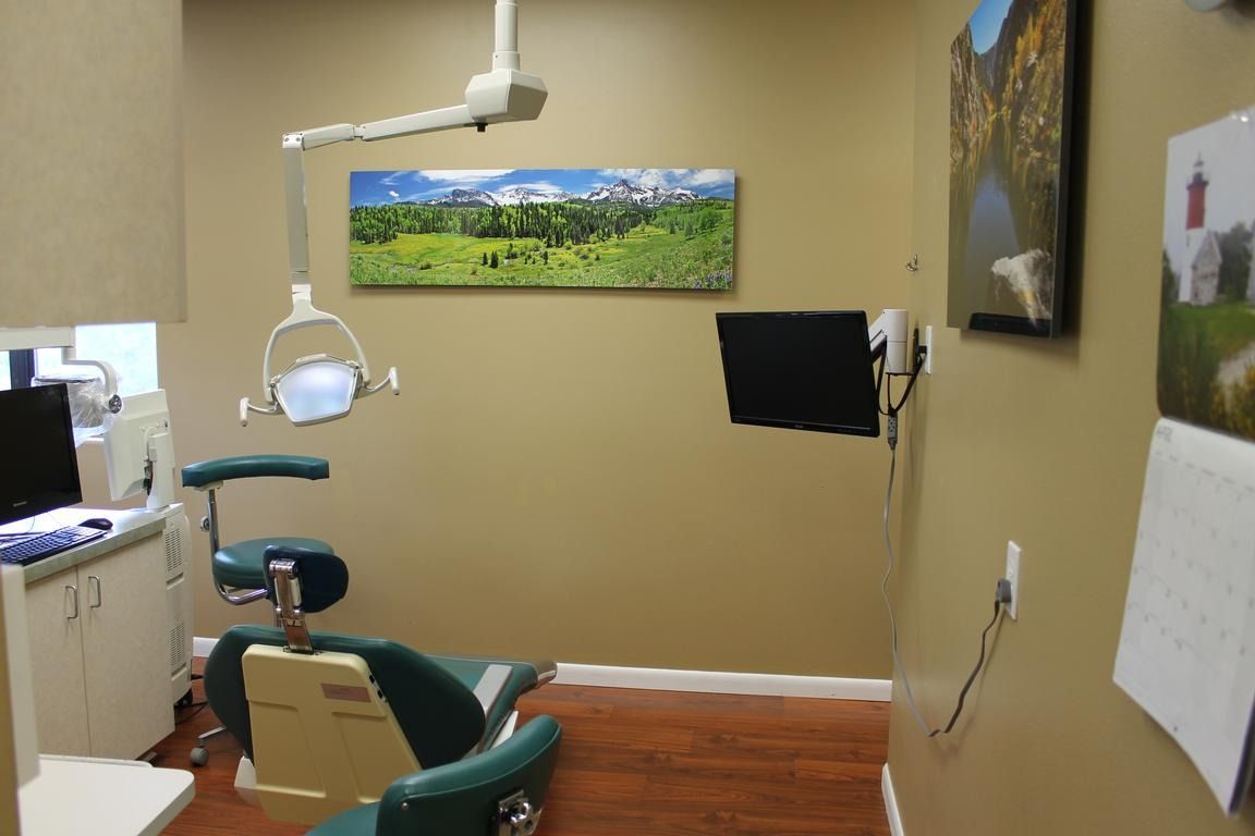 Dental exam room with chair, light, and artwork on the walls.