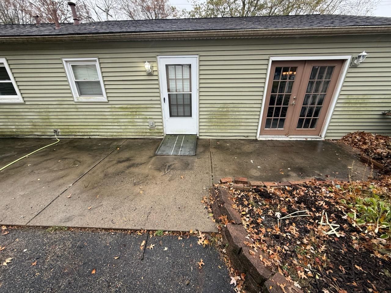 A green house with a white door and sliding glass doors.