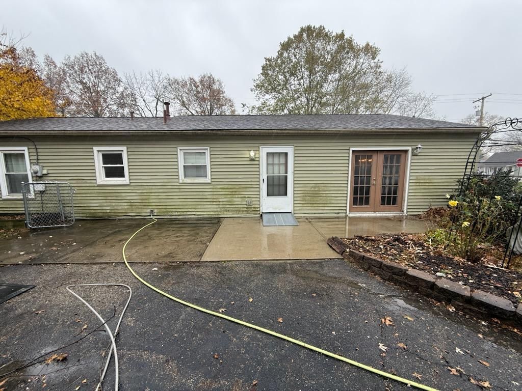 A green house with a white door and a hose in front of it before clean.