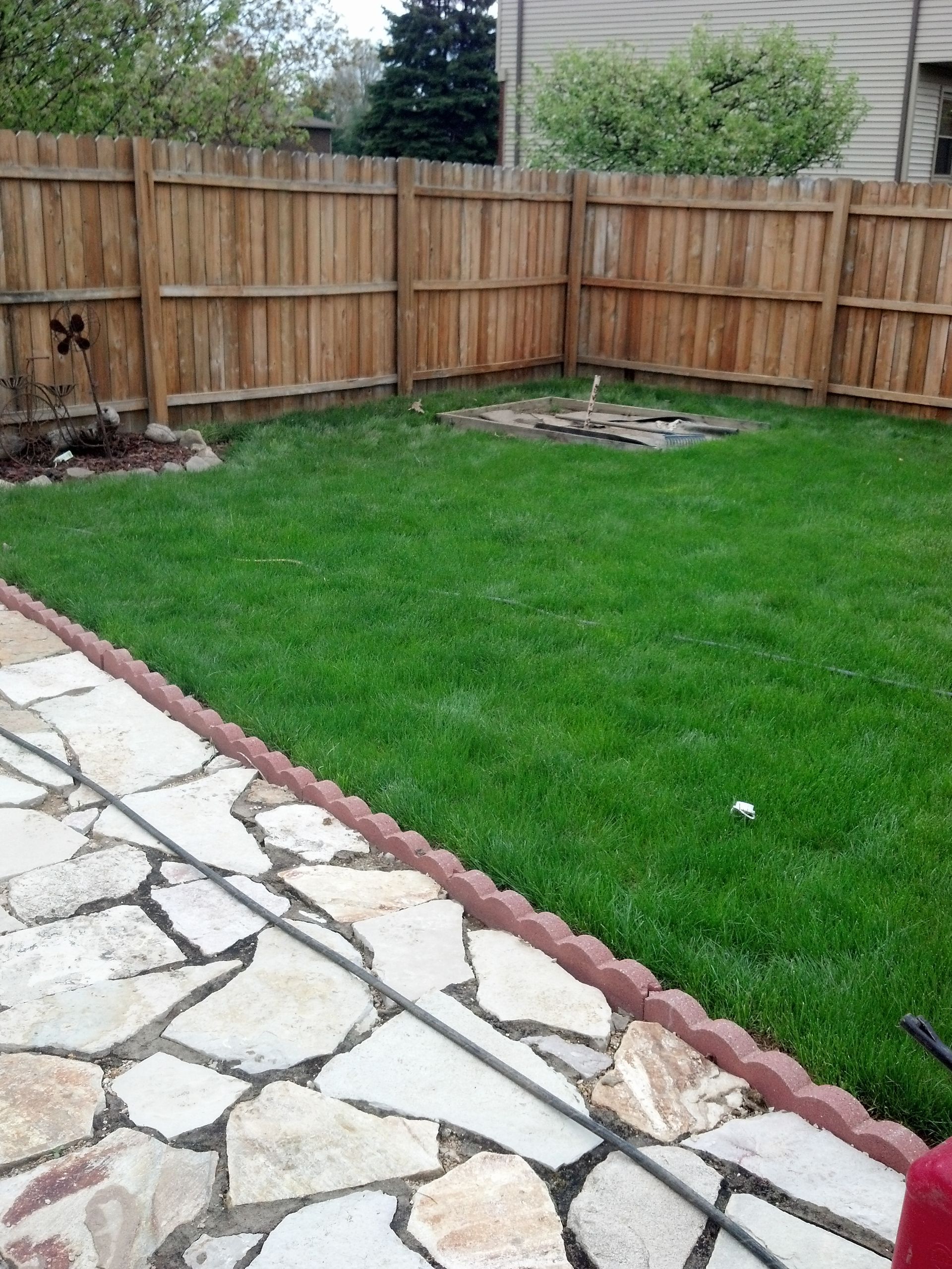 A backyard with a wooden fence and a stone walkway