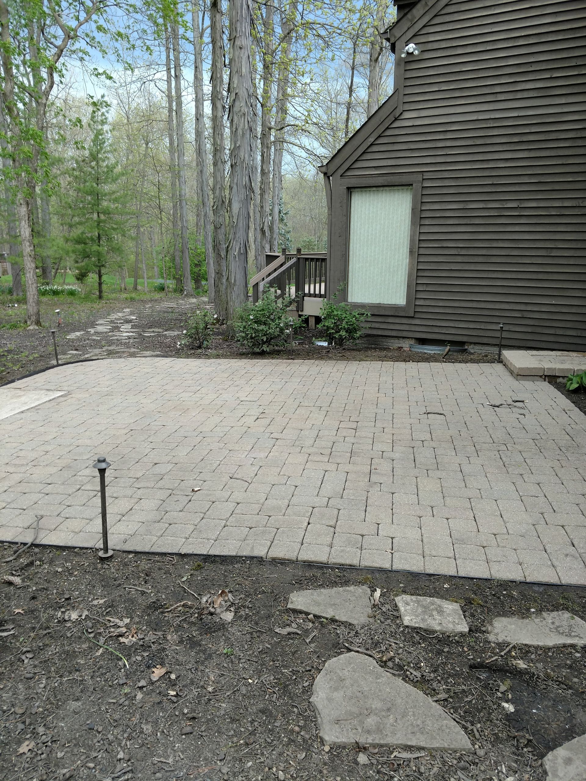 There is a patio in front of a house in the woods.