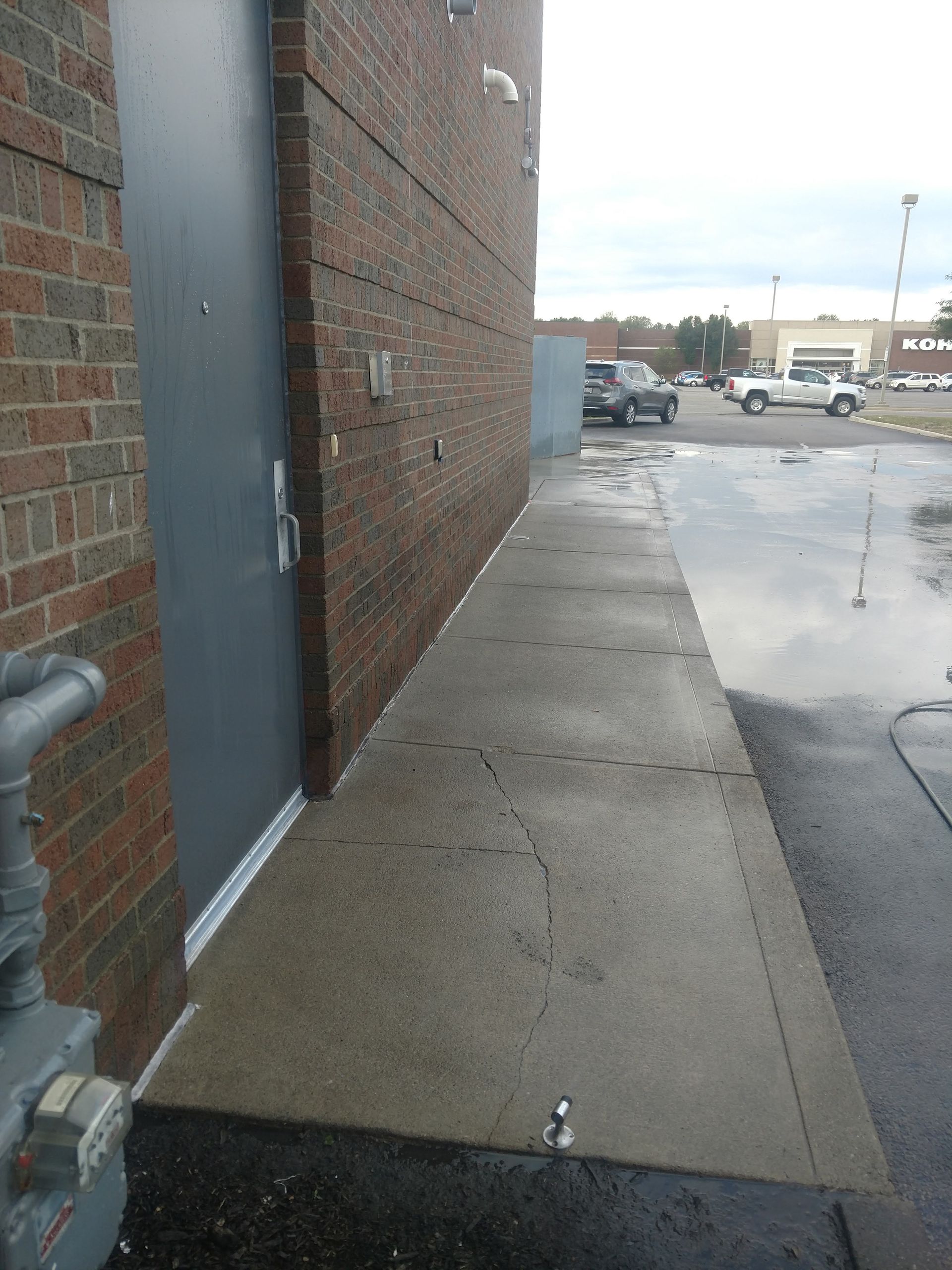A sidewalk next to a brick building with a door