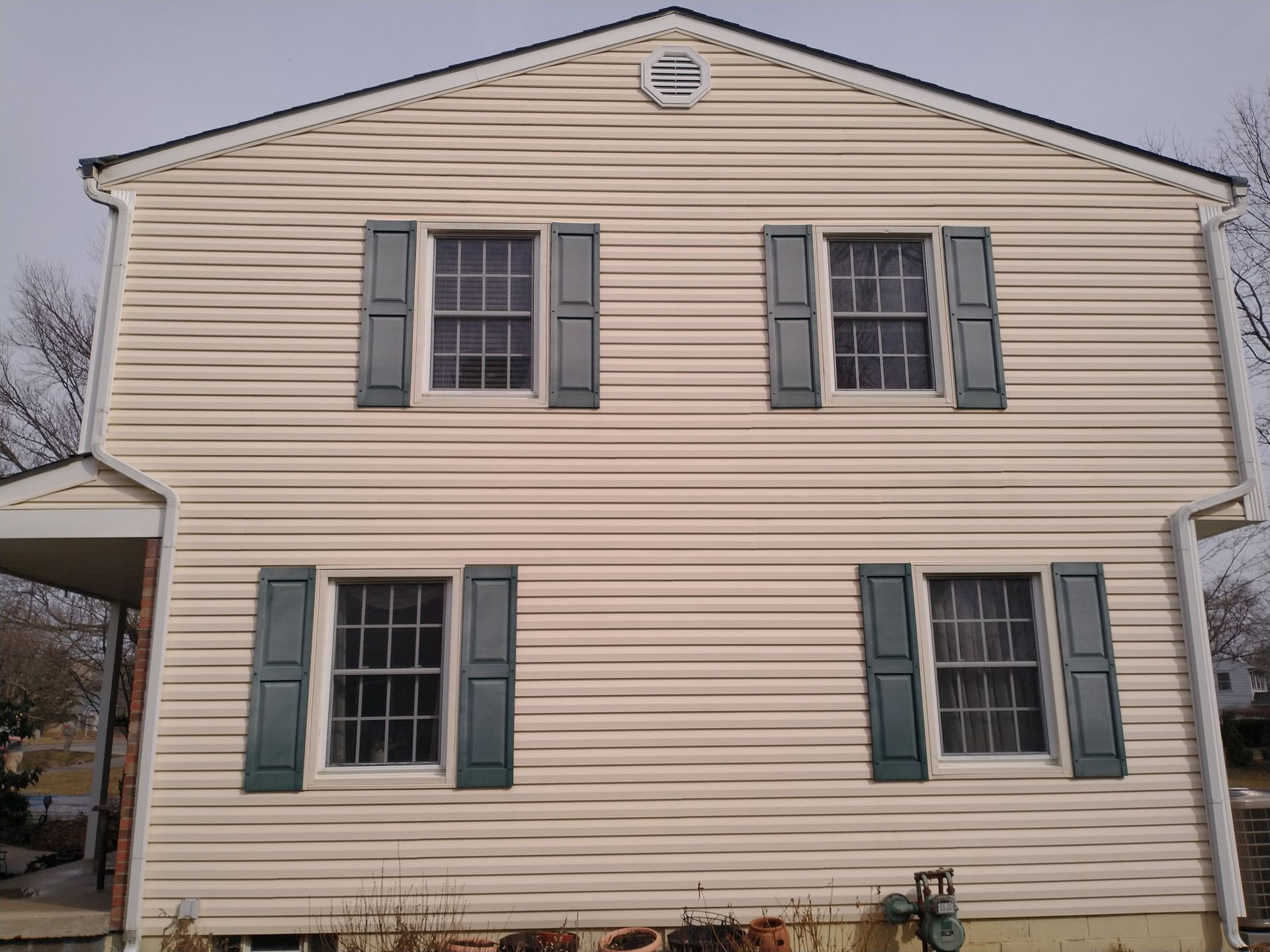 A white house with green shutters on the windows