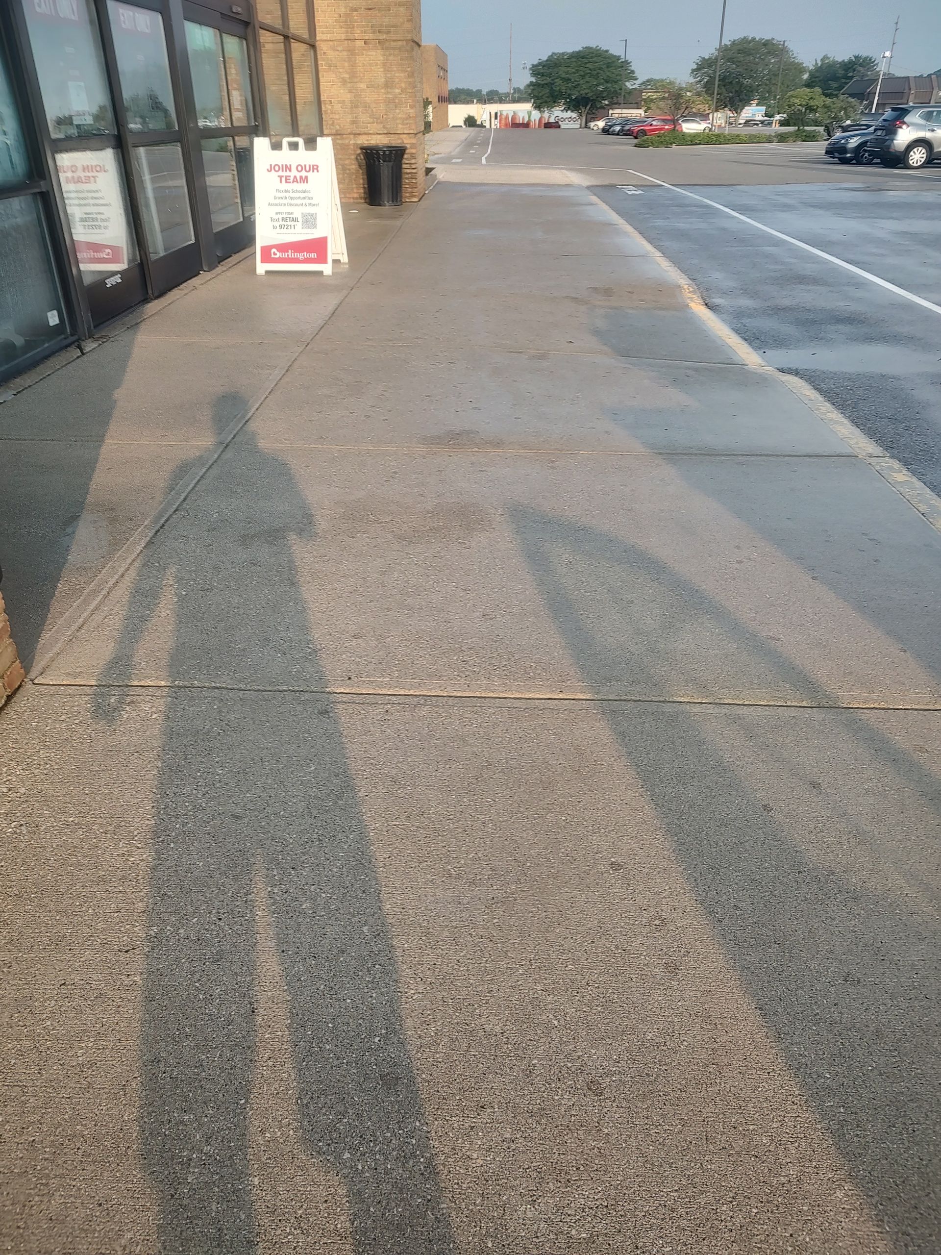 A shadow of a person is cast on a sidewalk in front of a building.
