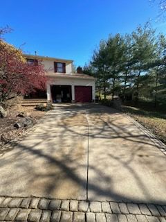A driveway leading to a house with a red garage door after clean.