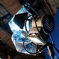 A studio spotlight mounted on a stand with a piece of blue translucent gel attached to the front.