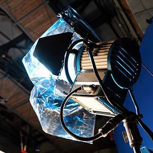 A studio spotlight mounted on a stand with a piece of blue translucent gel attached to the front.