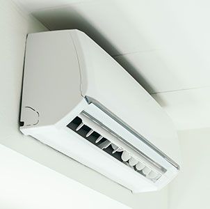 A white split-system air conditioner mounted on a corner wall.