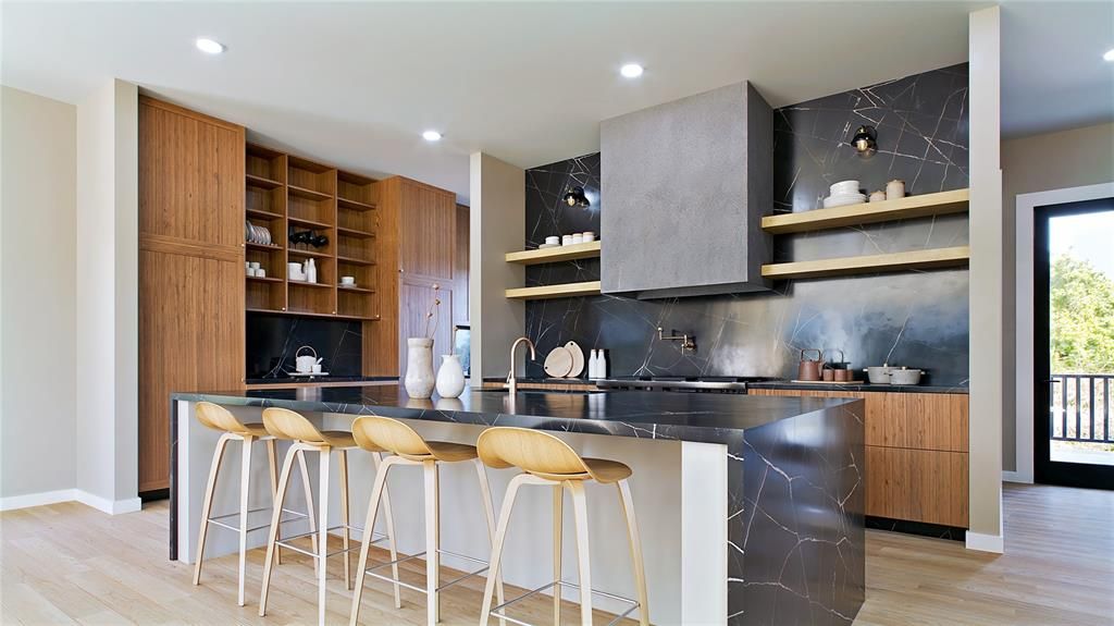 Modern kitchen with island seating, wood cabinetry, black marble backsplash, and stainless hood.