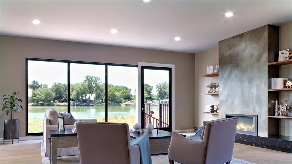 Living room with large windows overlooking water, fireplace, and neutral-colored furniture.
