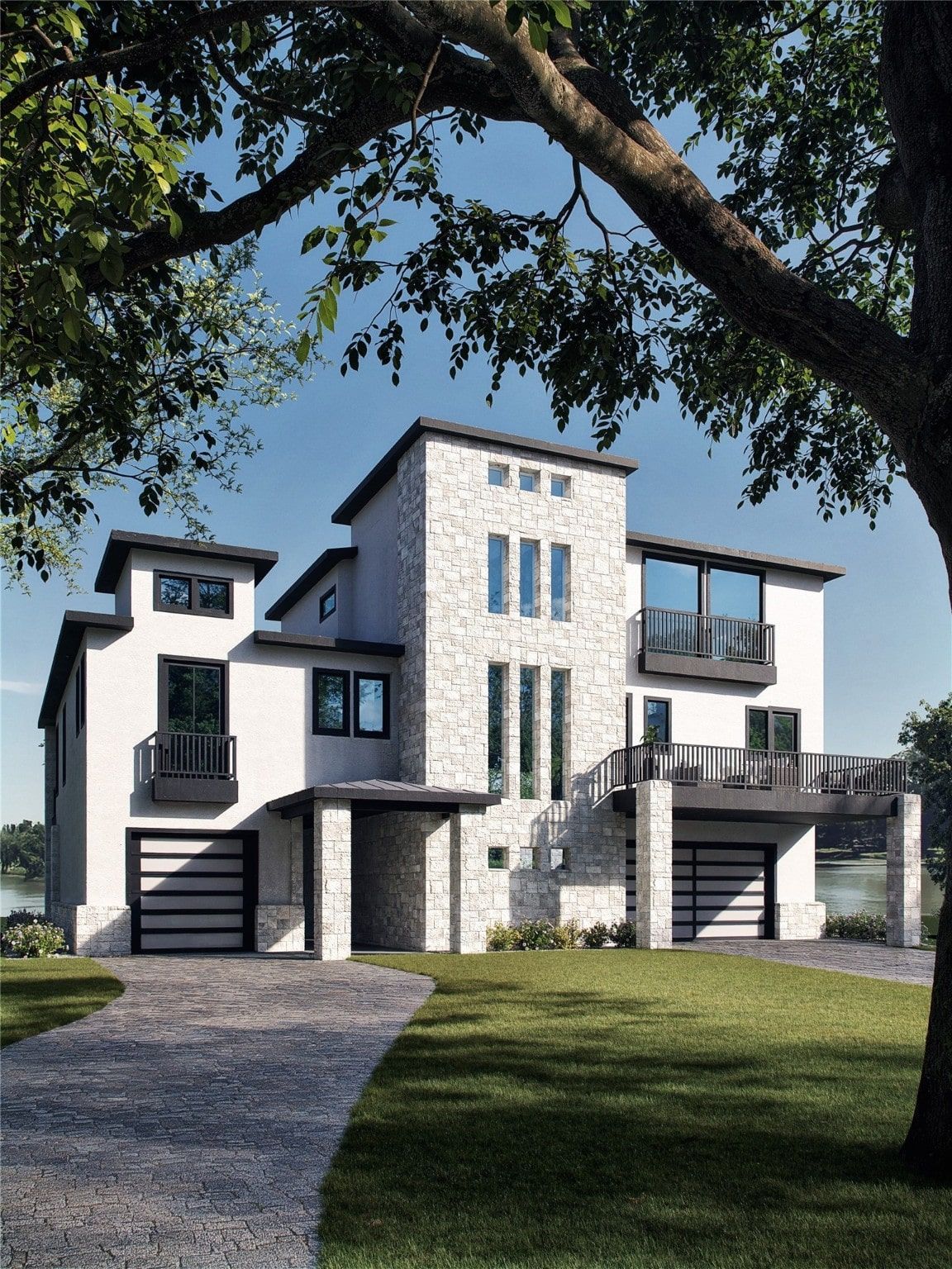 Modern white house with stone accents, two-car garage, and a curved driveway in a sunny setting.