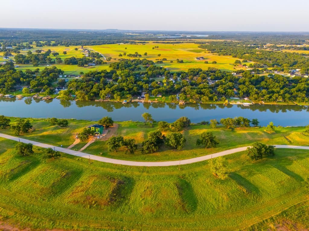 Green landscape with river, path, and grassy mounds under a clear sky.