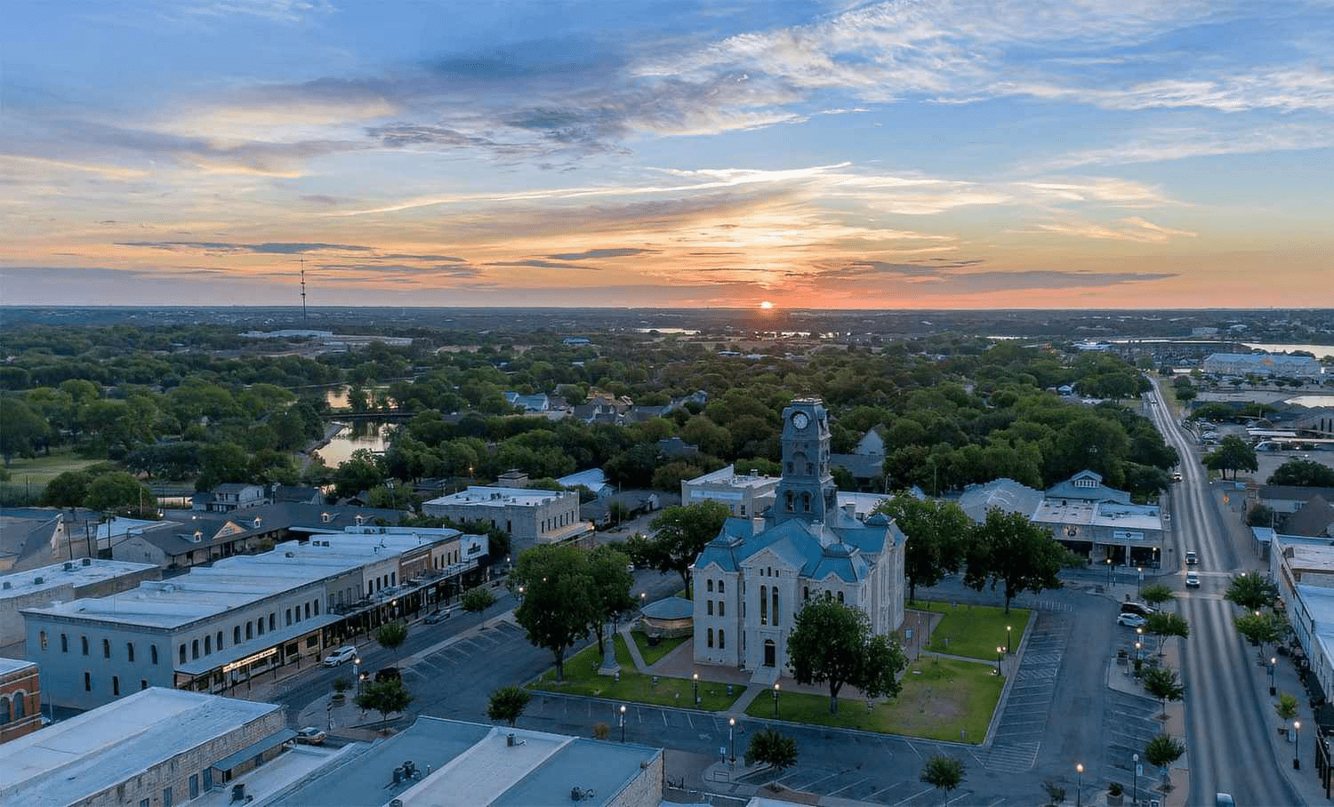 Aerial view of a town square with a courthouse bathed in the golden light of sunrise.