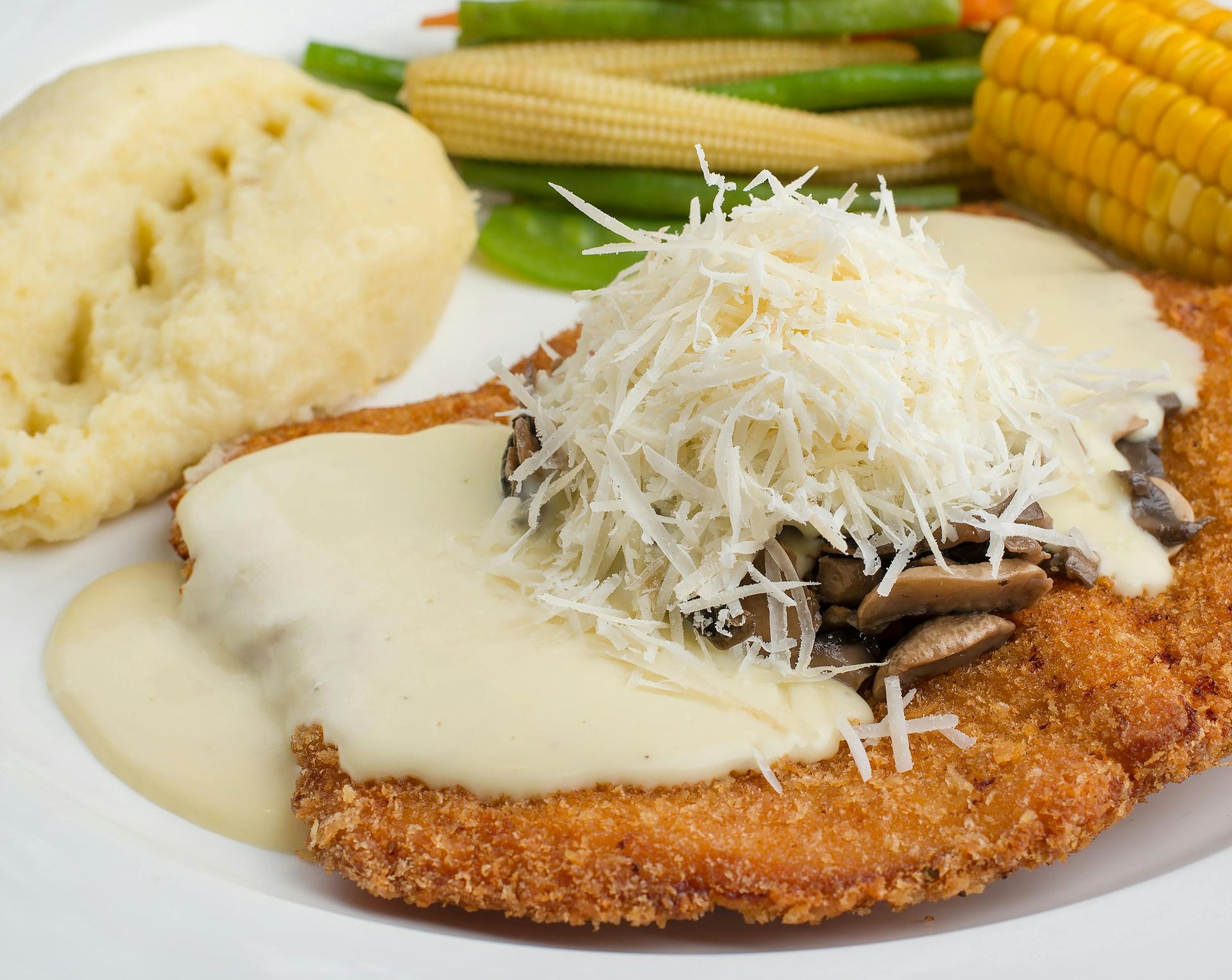 Breaded chicken with creamy sauce, mushrooms, and cheese, with mashed potatoes and vegetables.