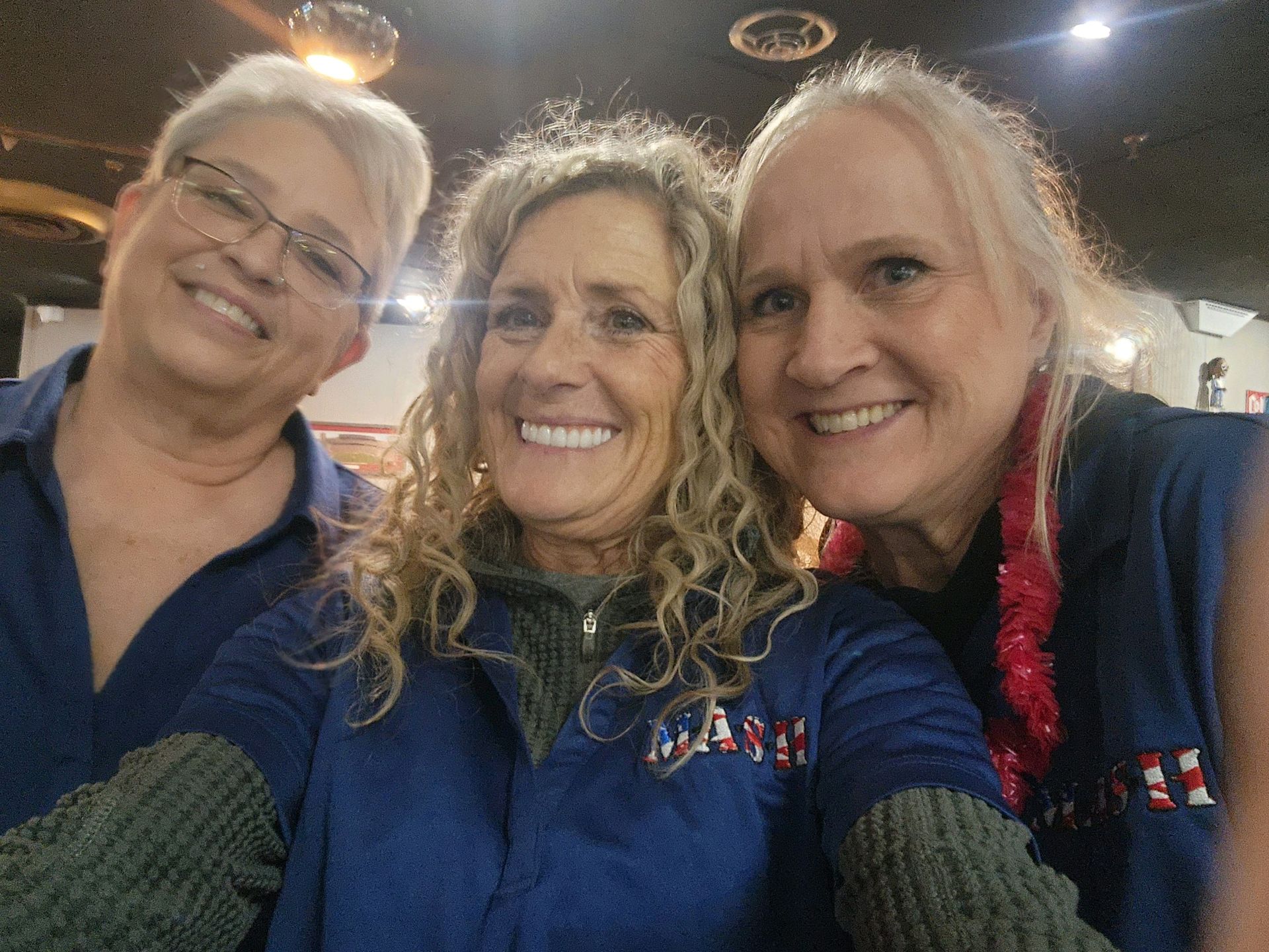 Three women are posing for a picture together and smiling.