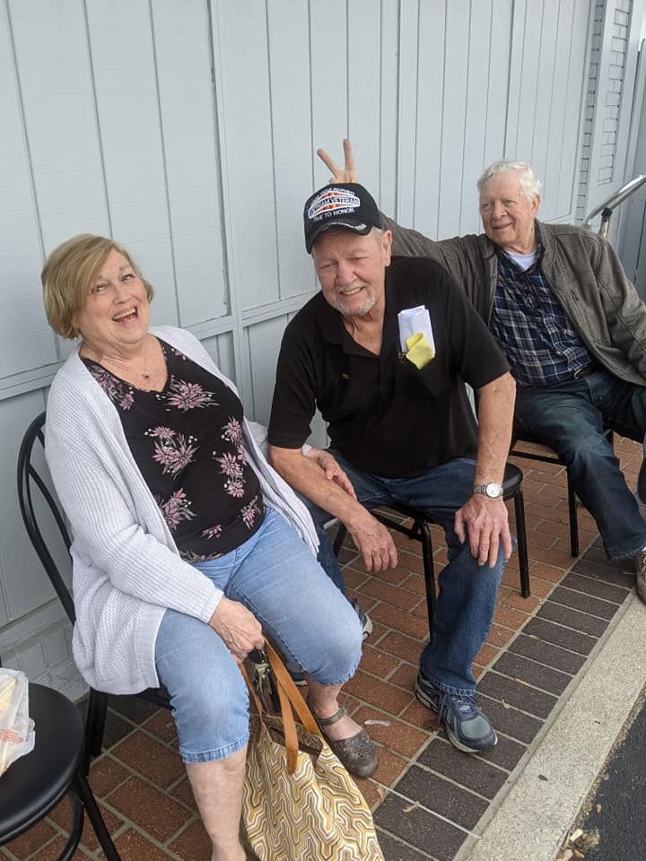 A group of people are sitting in chairs on a sidewalk.