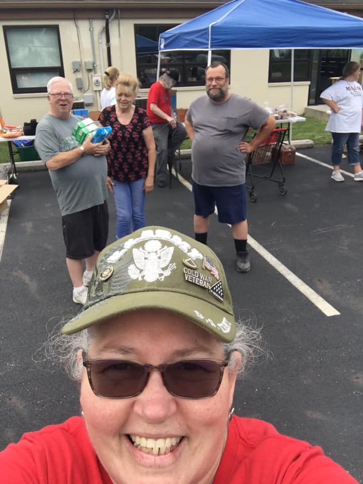A woman is taking a selfie with a group of people in a parking lot.