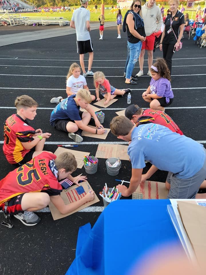 A group of children are sitting on the ground with one wearing a jersey with the number 25 on it