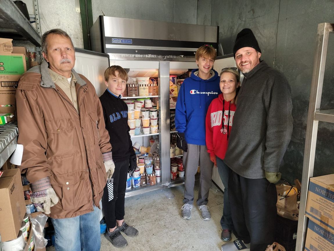 A group of people standing in front of a refrigerator filled with food