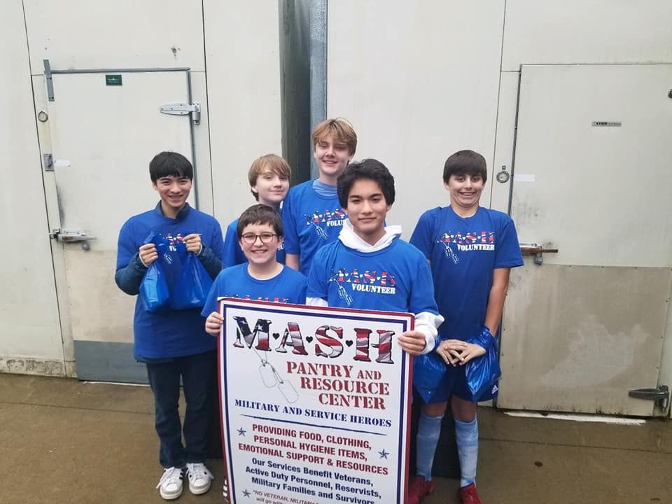 A group of young men are holding a sign that says mash pantry and resource center.