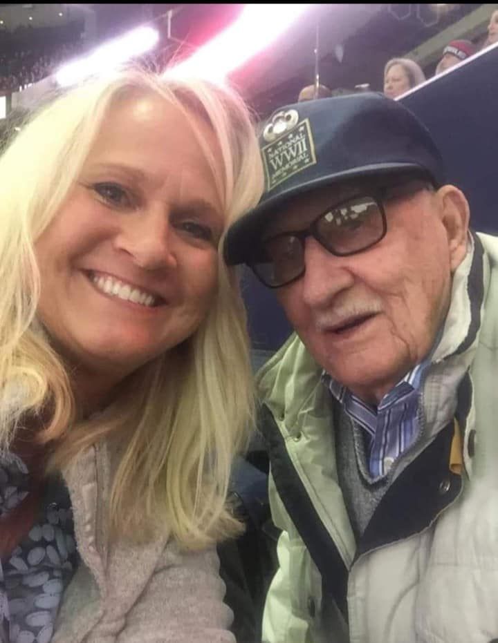 A woman and an older man are posing for a picture in a stadium.