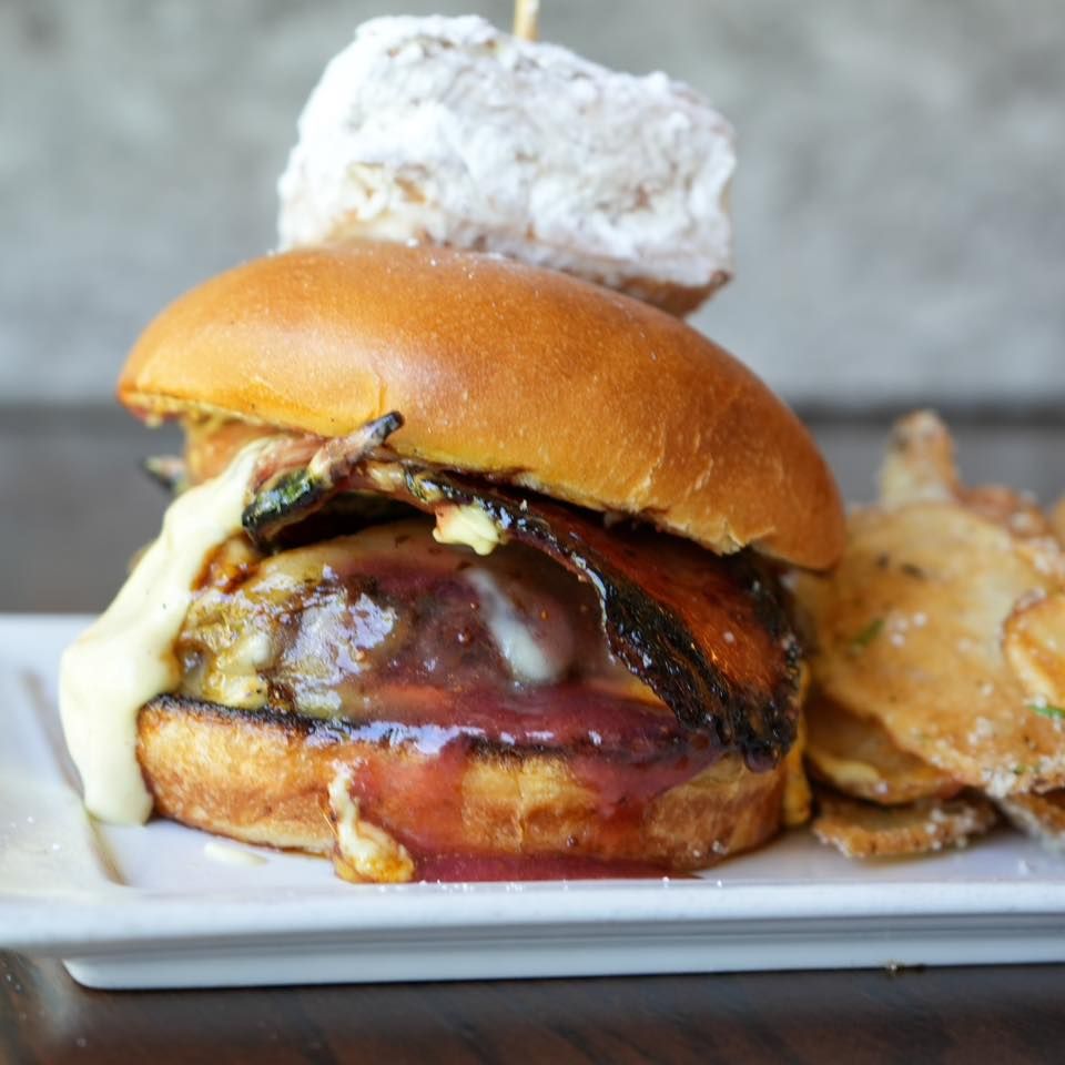 A close up of a hamburger on a plate with chips