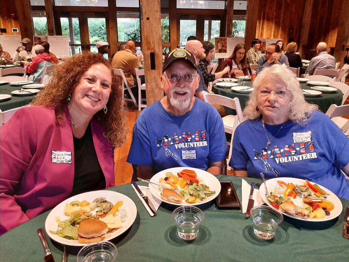 Three people are sitting at a table with plates of food.