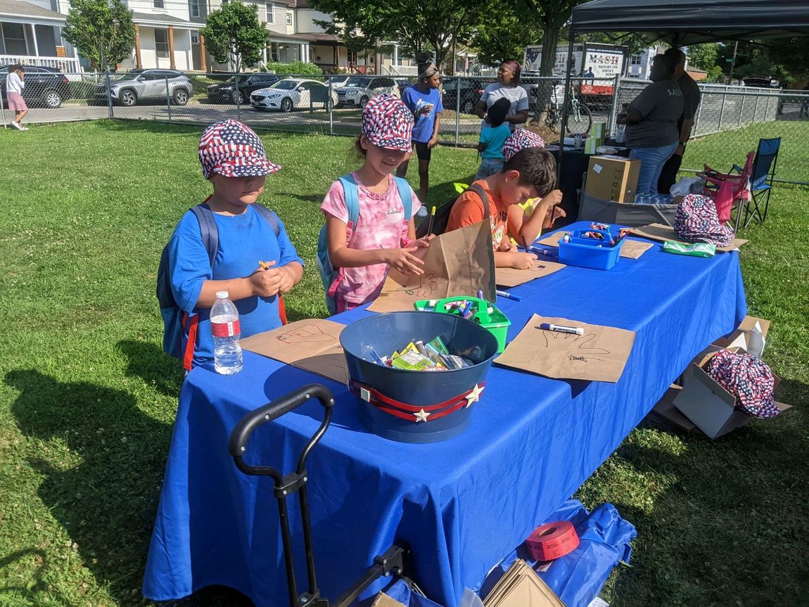 A group of children are sitting at a table in a park.