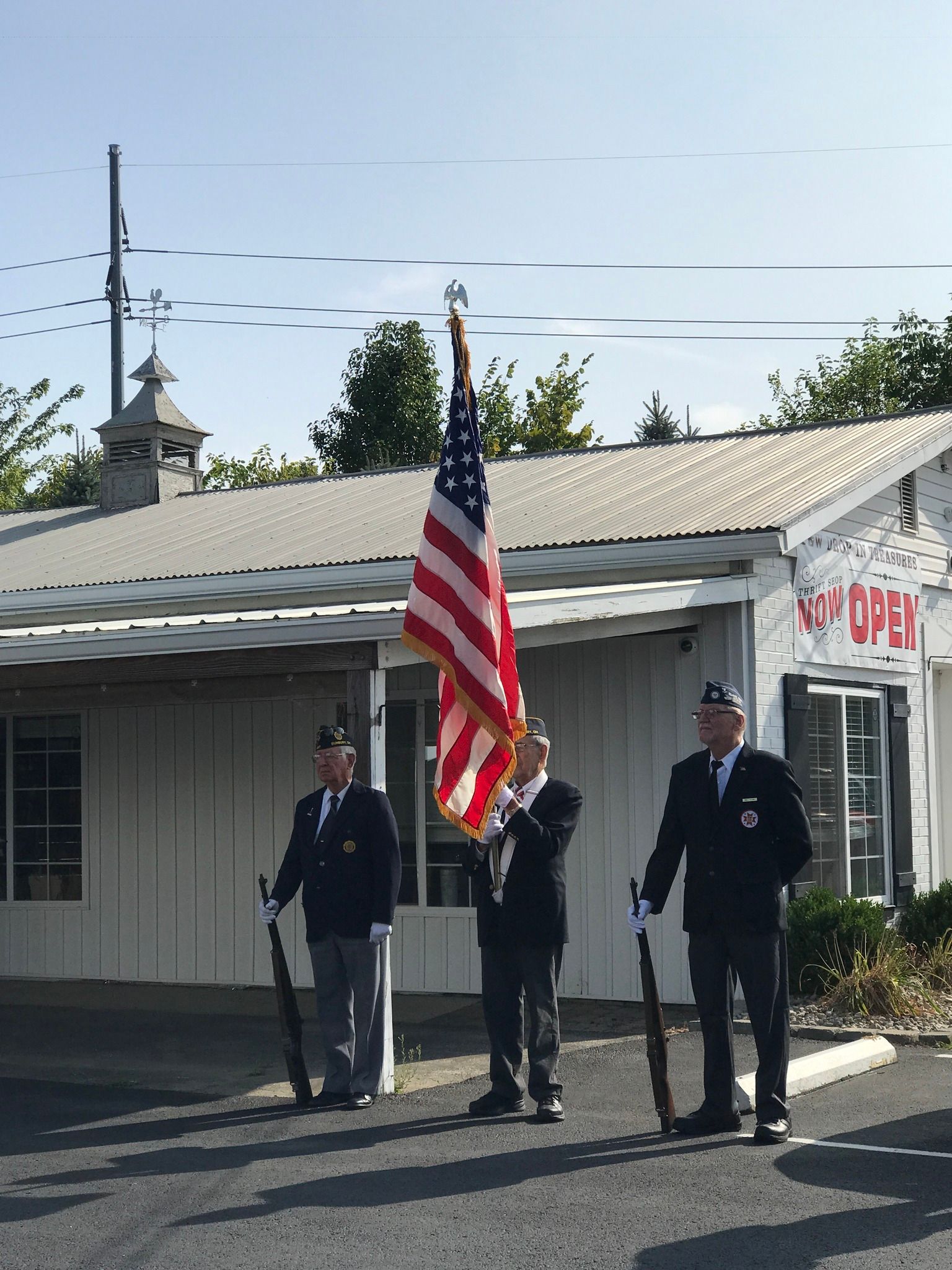 A group of men standing in front of a building holding umbrellas and a flag.