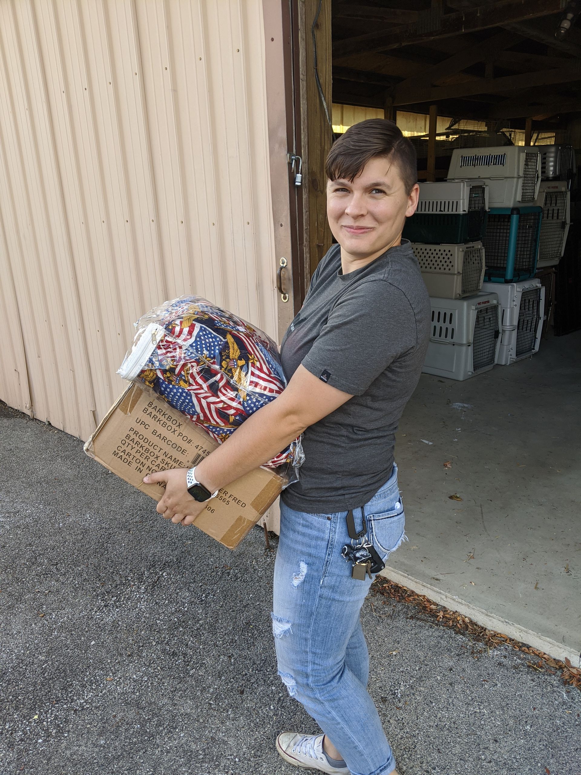 A woman is carrying a box of fireworks in front of a building.