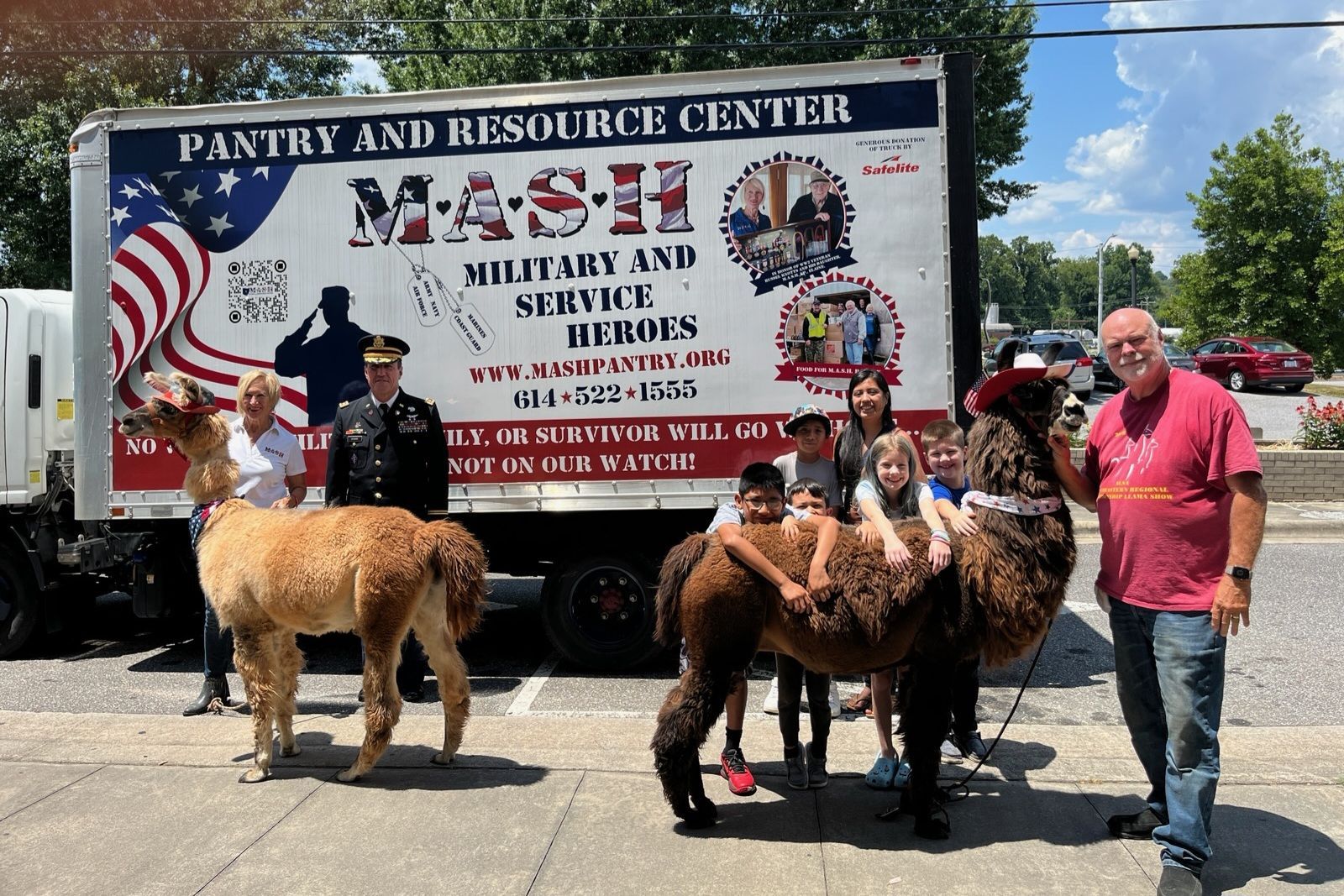 A group of people standing in front of a truck that says mash pantry and resource center.