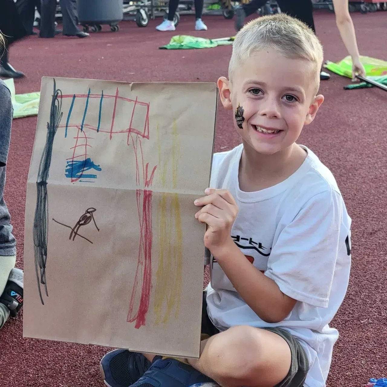 A young boy is holding a piece of paper with a drawing on it