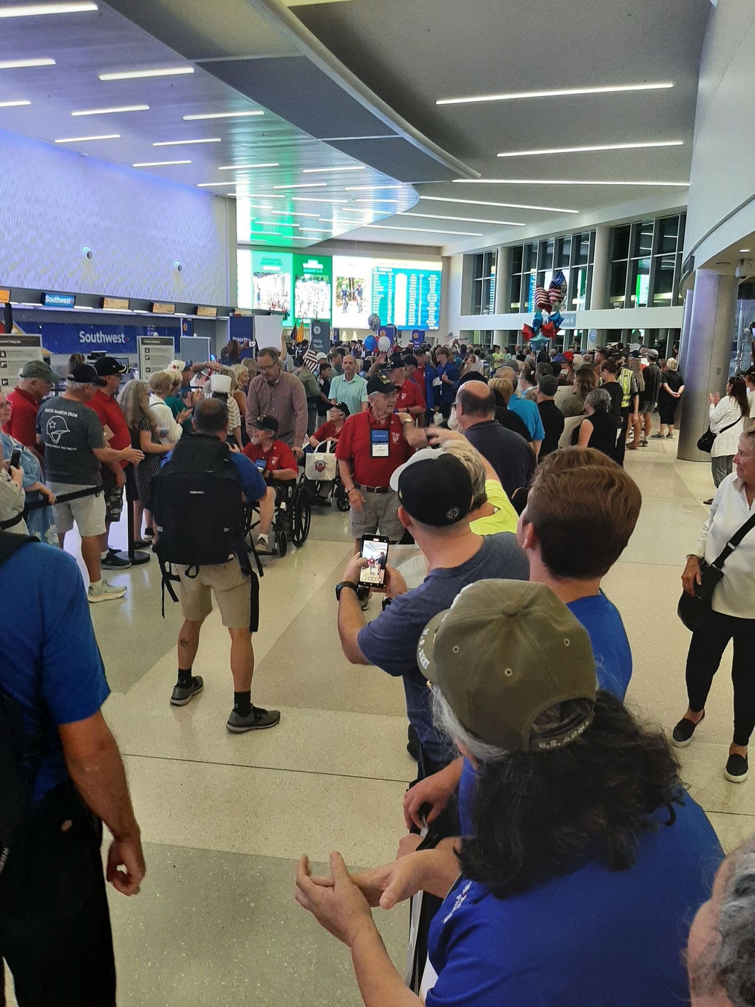 A large group of people are standing in an airport waiting to board a plane.