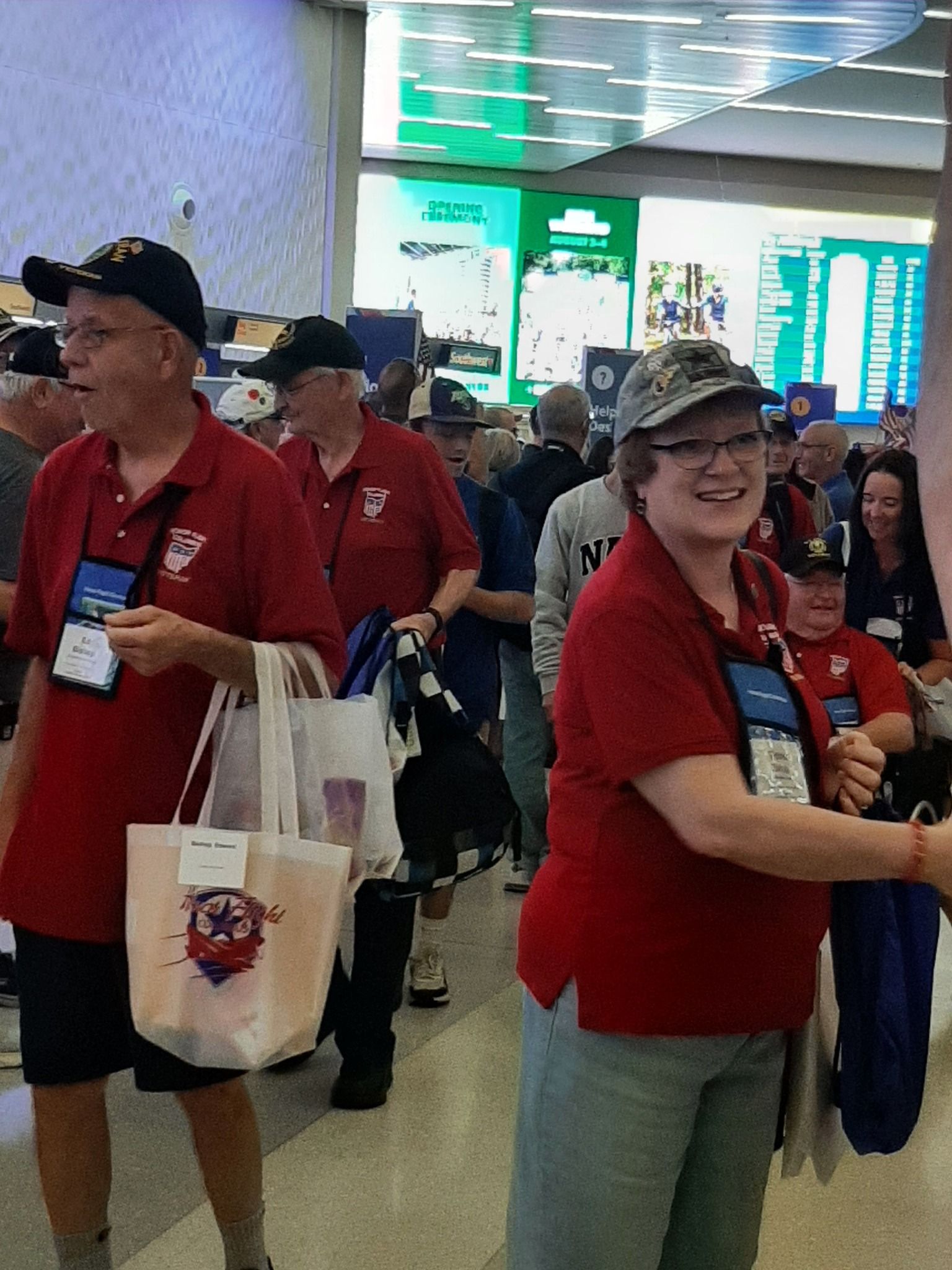 A group of people in red shirts are walking down a hallway