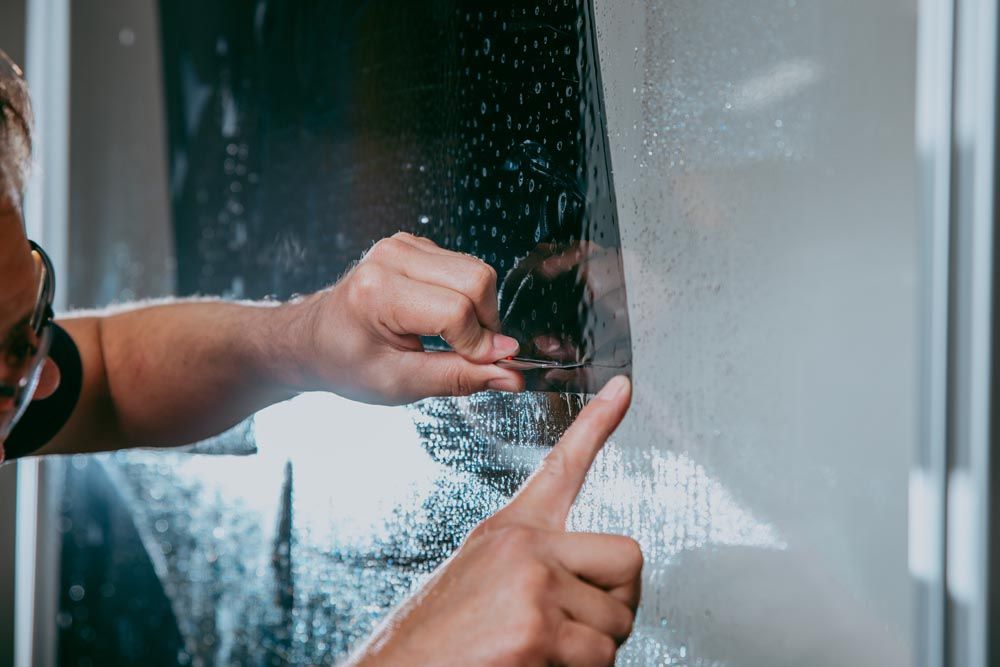 A person is applying tinted glass to a window.