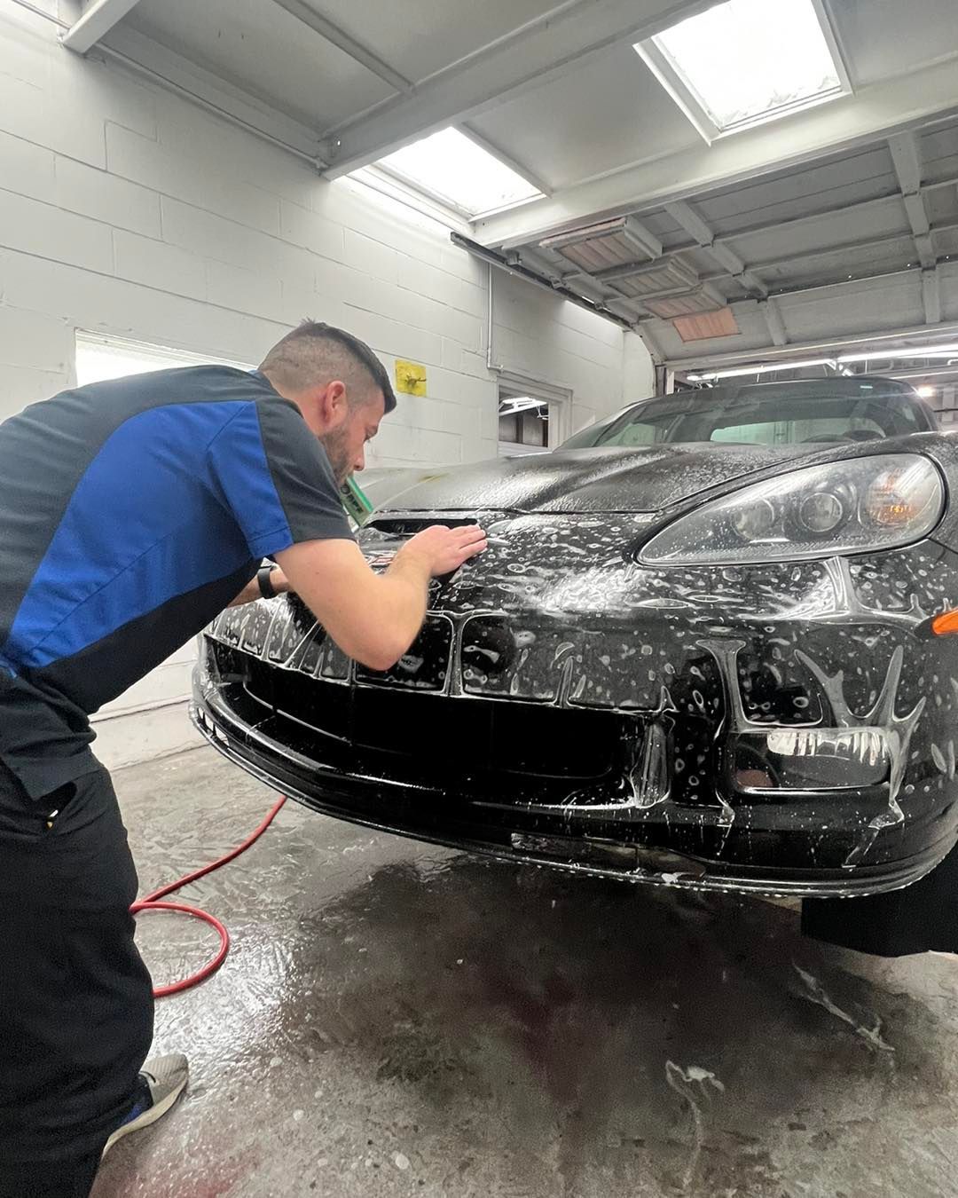 A man is washing a car in a garage.