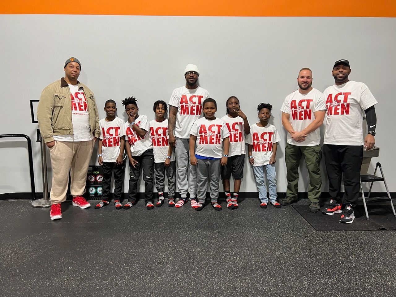 A group of boys and men in matching white t-shirts that say 