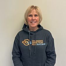 Woman with blonde hair wearing a dark grey hoodie with 