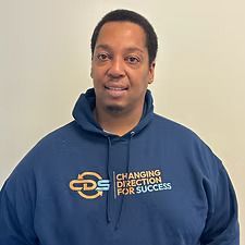 A man wearing a blue hooded sweatshirt with the logo 