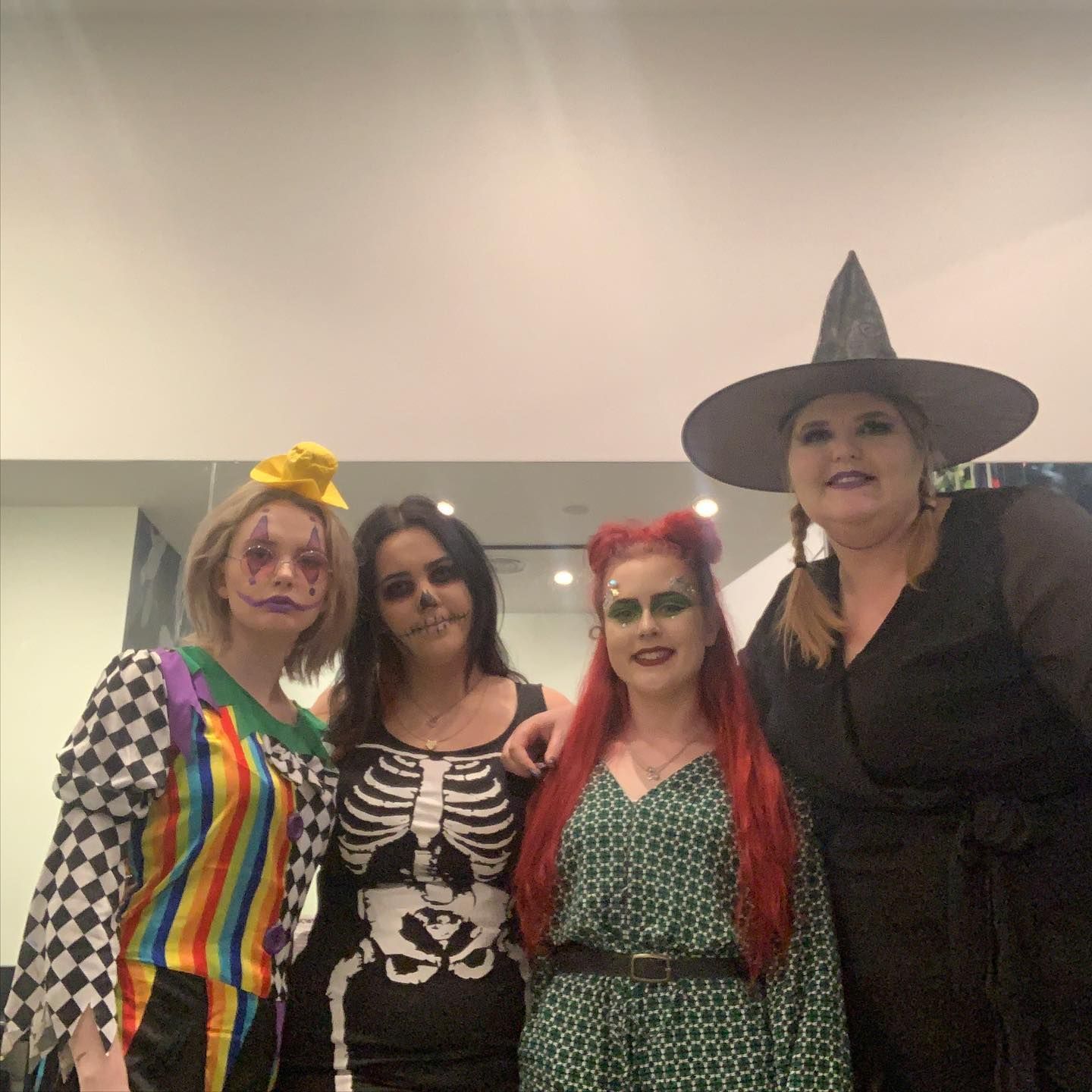 Four people in Halloween costumes: clown, skeleton, Poison Ivy, and witch, smiling indoors. — Wow! Excellence in Hair in Toowoomba, QLD