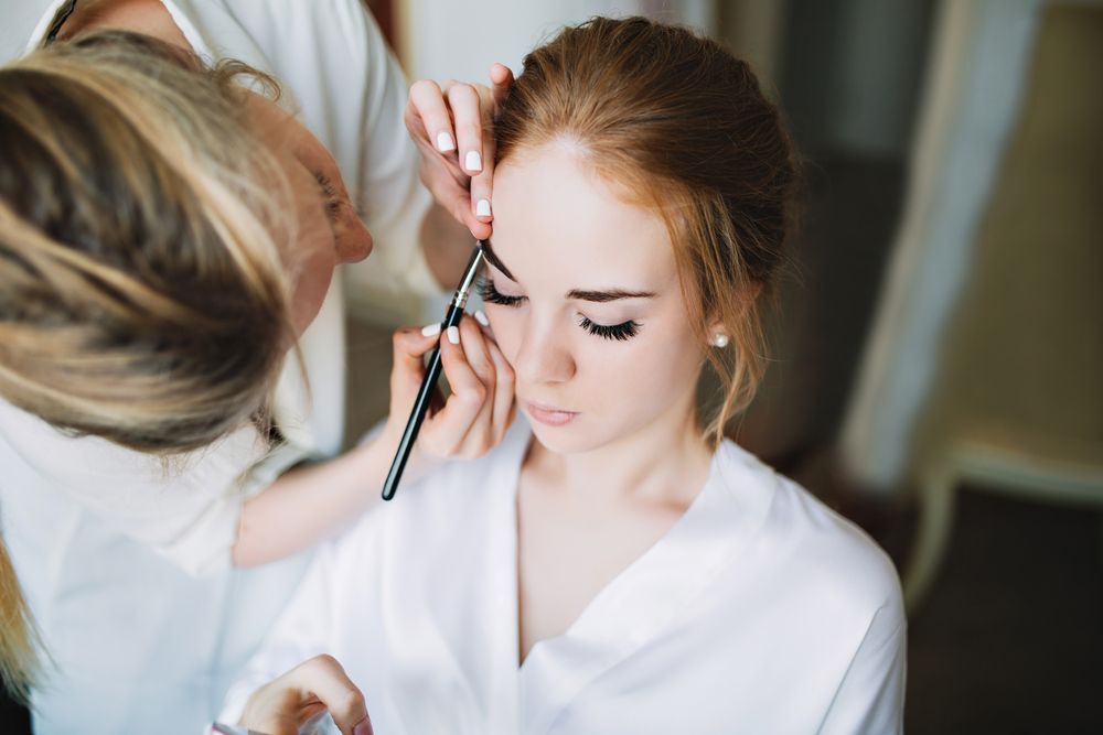 Makeup Artist Applying Eyebrow Makeup on a Young Woman — Wow! Excellence in Hair in Toowoomba, QLD